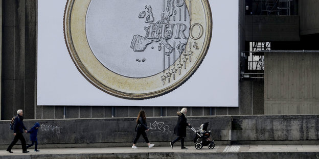 Menschen laufen auf einem leicht ansteigendem Weg unter einem großen Euro-Plakat