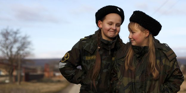 zwei jugendliche Mädchen in Uniform grinsen sich an