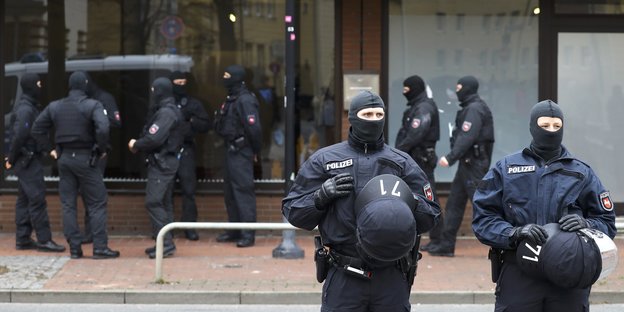Polizisten in Montur stehen vor einem Gebäude