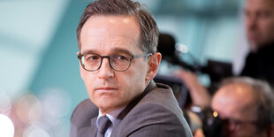 Heiko Maas sitzt auf einer Pressekonferenz vor Journalisten