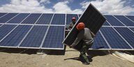Menschen tragen Solarpanele bei einem Kraftwerk