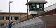 Ein Mann arbeitet an einem Nato-Draht auf einer Gefängnismauer