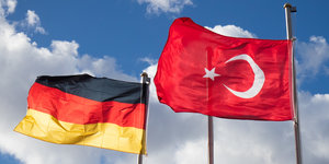 Eine deutsche und eine türkische Flagge wehen im Wind