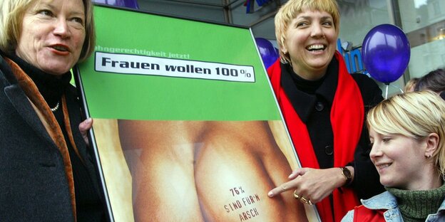3 Grünensprecherinnen, darunter Claudia Roth, halten ein Plakat mit einem nackten Männerhintern und der Aufschrift "76% sind für'n Arsch"