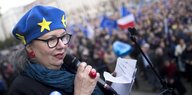 Eine Frau mit einer Mütze mit den Europasternen spricht auf der Pulse of Europe Versammlung in Berlin