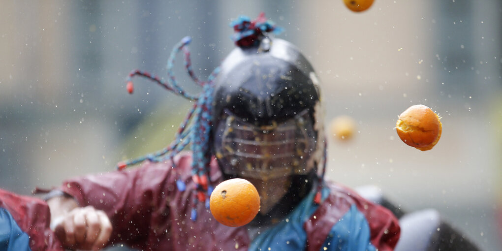 Ein Mann mit einer Maske haut auf Orangen