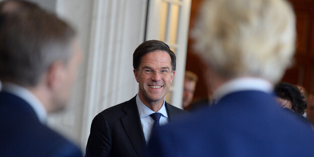 Mark Rutte lacht, als er nach der Wahl Geert Wilders begegnet, der auf dem Foto von hinten zu sehen ist