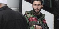 Syprischer Kämpfer gegen Assad steht mit Maschinengewehr vor einem Bus