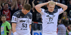 Zwei niedergeschlagene Handballspieler vor Zuschauerrängen