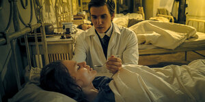Szene aus "Charité" Patientin liegt im Bett, sie wird von einem Arzt gefüttert