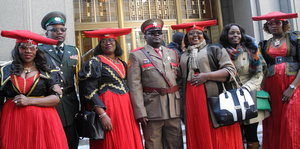 Angehörige der Herero in roten Kleidern und Uniformen vor dem Gericht in New York