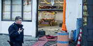 Ein Polizist läuft am von der Explosion zerstörten Eingang des Essener Sikh-Tempels vorbei