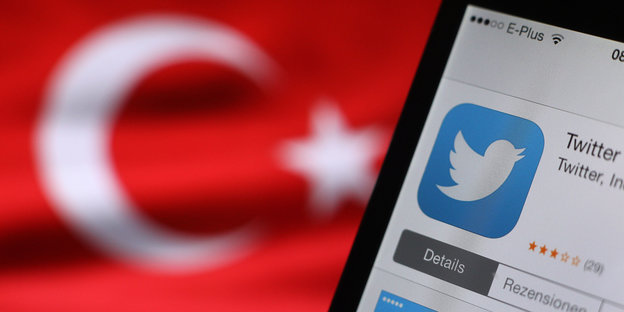 Im Hintergrund eine türkische Nationalflagge, rechts im Vordergrund ein Smartphone, auf dem im App-Store Twitter heruntergeladen wird