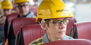 Eine Frau sitzt im Bus und hat einen Bauhelm auf