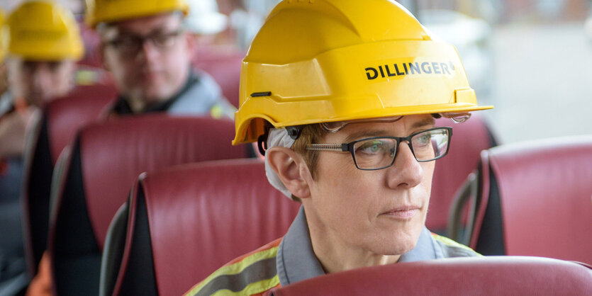 Eine Frau sitzt im Bus und hat einen Bauhelm auf