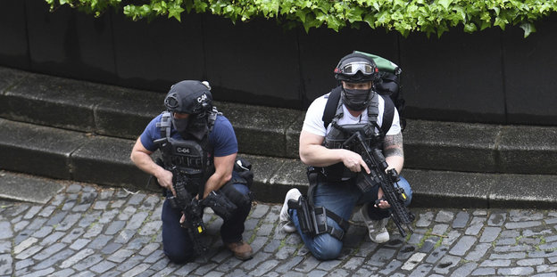 Zwei bewaffnete Polizisten knien in Deckung