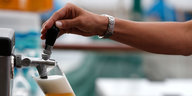 Zwei Hände zapfen ein kleines Bier aus einer Zapfanlage