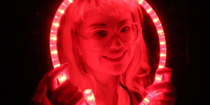 Eine junge Frau, die nur von einem roten Licht angestrahlt wird, lächelt