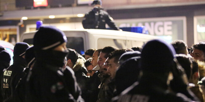 Polizisten stehen vor einer Gruppe Männer