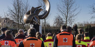Rettungskräfte stehen in orangefarbenen Westen mit dem Rücken zum Betrachter bei einer Gedenkminute am Brüsseler Flughafen