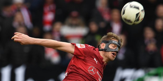 Ein Fußballer mit Maske versucht sich an einem Kopfball