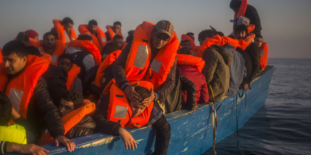 Menschen mit Rettungswesten sitzen in einem Boot