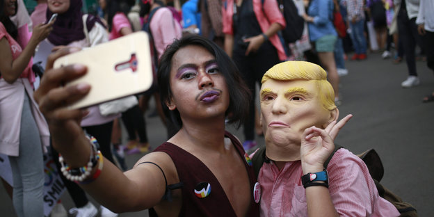 Ein Aktivist macht ein Selfie mit einer Aktivistin, die eine Trump-Maske trägt