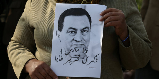 Hände halten ein Bild Mubaraks