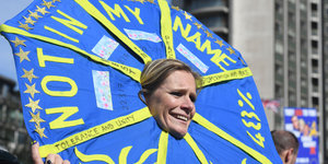 Eine Frau trägt einen blauen Schirm bei einer Demonstration