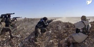 Vier Kämpfer liegen hinter einem flachen Steinwall und zielen mit ihren Waffen in die Wüste