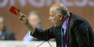 Jibril Rajoub steht an einem Rednerpult und hält eine rote Papierkarte in der Hand
