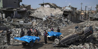 Ehemalige Bewohner der zerstörten Häuser transportieren aus den Trümmern geborgene Tote ab