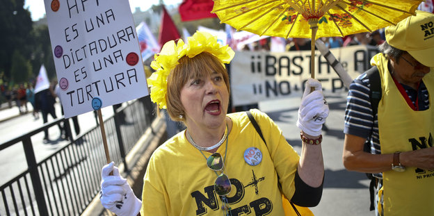 Ein Frau mit einem gelben Sonnenschirm bei einer Demonstration