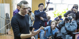 Alexei Nawalny steht in einem Gerichtssaal umringt von Journalisten