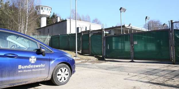 Ein blaues Auto vor einem grünen Kasernentor