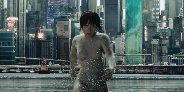 Ein Cyborg läuft durch Wasser, im Hintergrund eine Stadt
