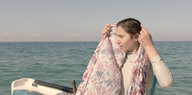 Ein Mädchen auf einem Boot zieht sich ein Tuch über den Kopf