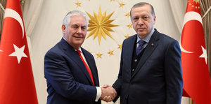 Rex Tillerson und Erdogan halten jeweils die Hand des anderen und starren in die Kamera