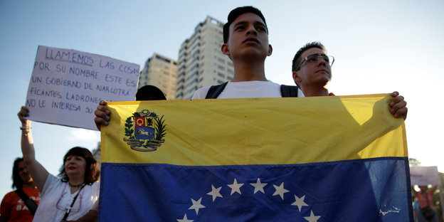 Ein Unterstützer der Opposition hält die venezolanische Flagge hoch und guckt kampflustig