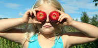 Ein Mädchen hält sich zwei Äpfel vor die Augen