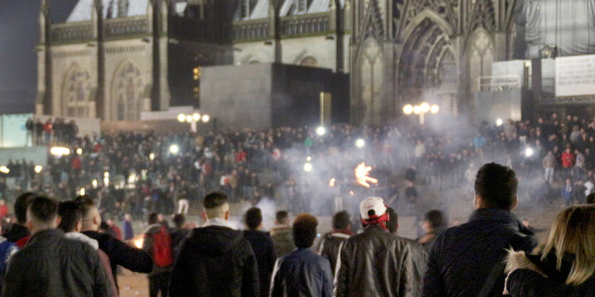 Viele Männer stehen im Nebel von Böllern vor dem Kölner Dom