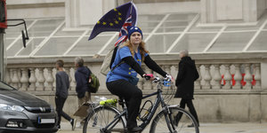 Eine Fahrradfahrerin hat an ihrem Rucksack eine Flagge der Europäischen Union angebracht