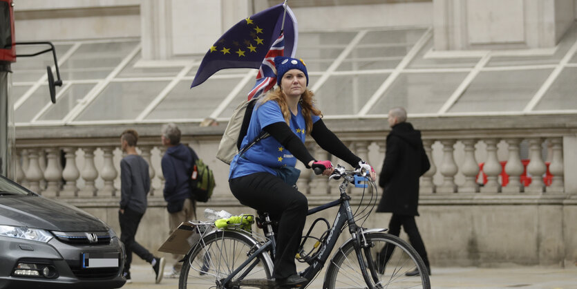 Eine Fahrradfahrerin hat an ihrem Rucksack eine Flagge der Europäischen Union angebracht