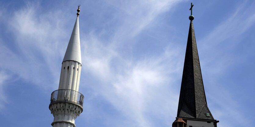 Minarett- und Kirchturm vor blauem Himmel