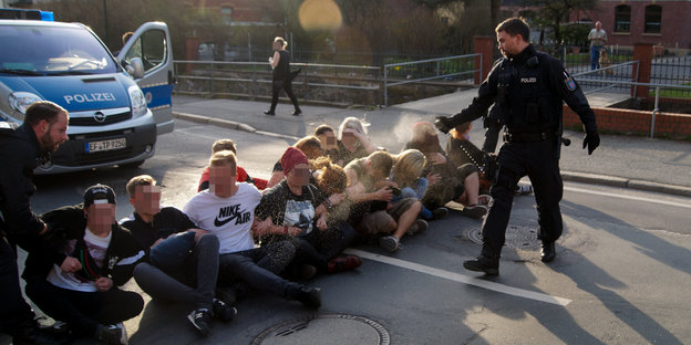 Ein Polizist sprüht Demonstranten einer Sitzblockade Pfefferspray ins Gesicht