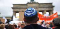 Eine Menschenmenge steht vor dem Brandenburger Tor, ein Mann mit Kippa ist zentral im Bild zu sehen