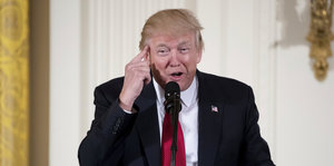 Donald Trump hält den Zeigefinger an die Schläfe
