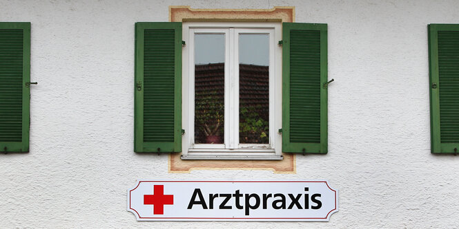 Ein geöffneter Fensterladen, daruntern ein Schild mit der Aufschrift „Arztpraxis“