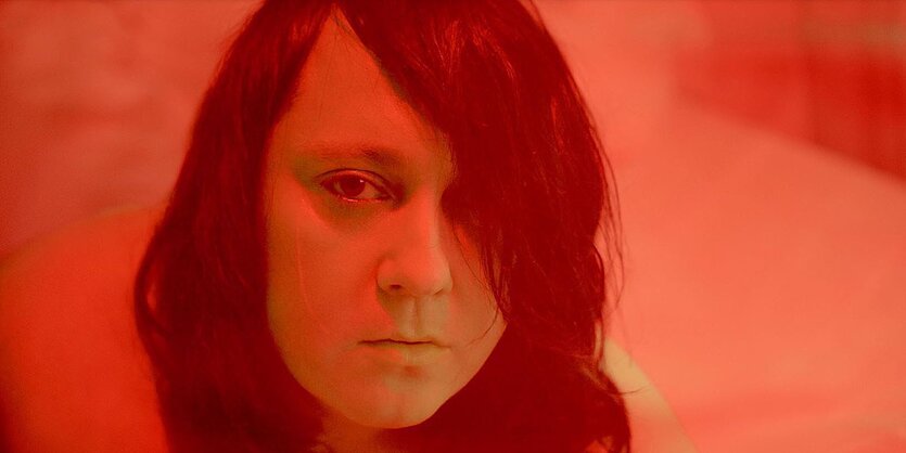 Das Gesicht der Sängerin Anohni, das durch einen Filter in rotes Licht gehüllt ist