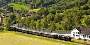 Eisenbahnzug vor grüner Berglandschaft